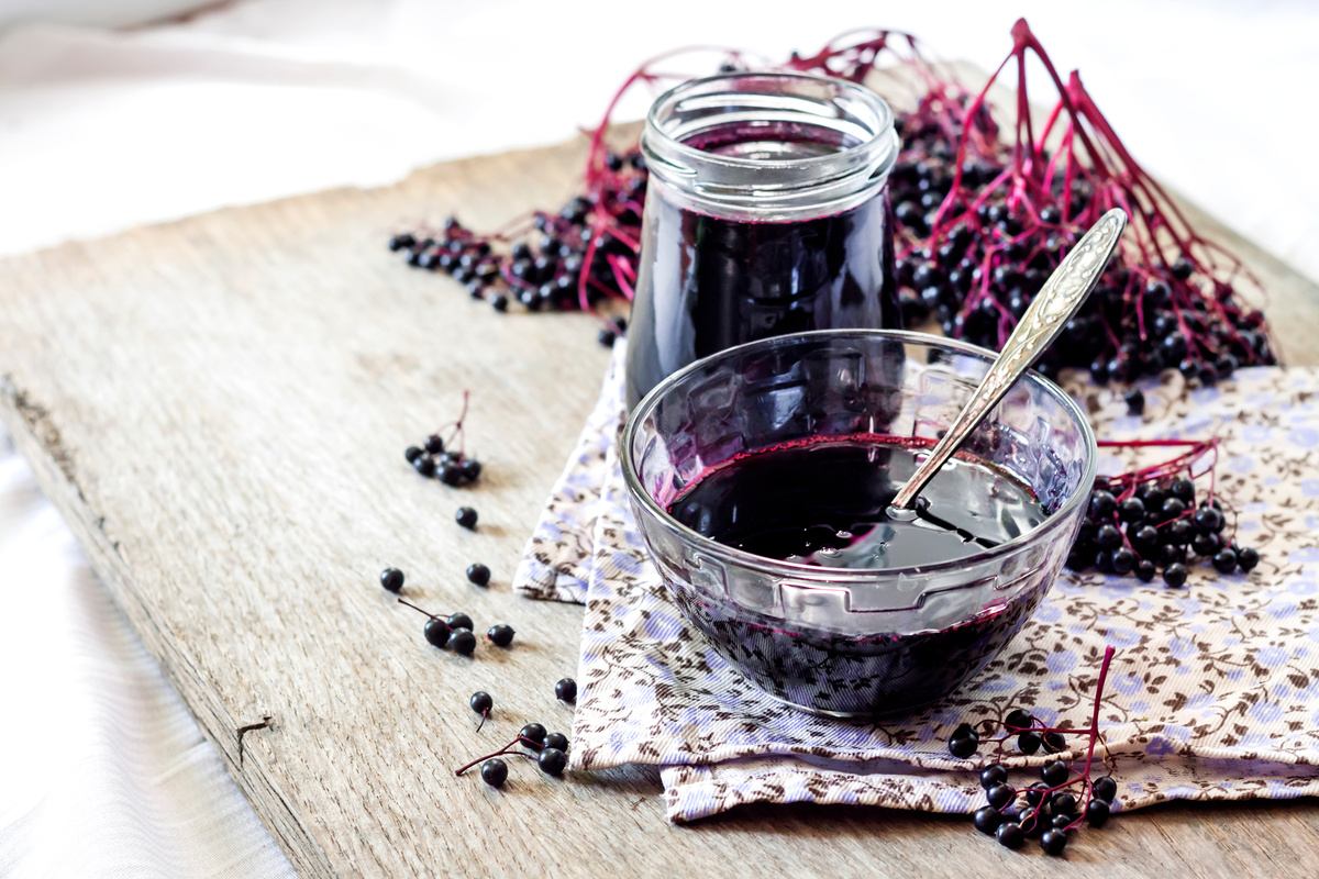 Homemade black elderberry syrup in glass bowl and jar