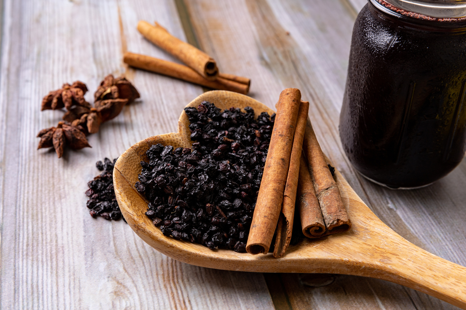 Jar of Elderberry Syrup on a wooden table.